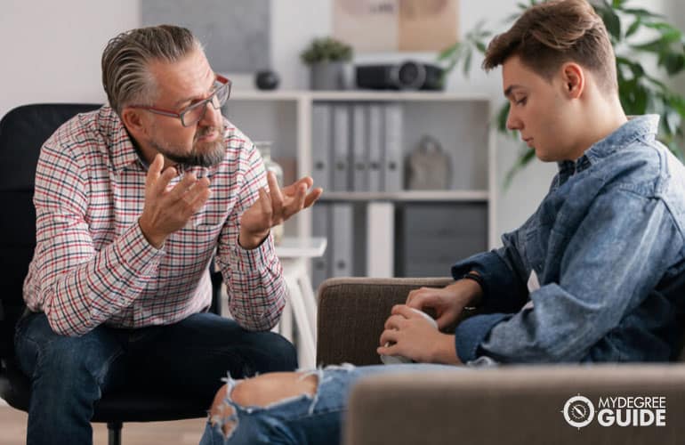 consejero masculino hablando con un adolescente en su oficina