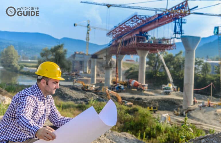 trabajador de la construcción mirando el plan de construcción del puente de la carretera