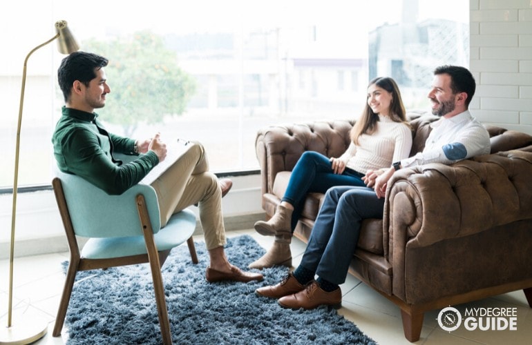 Terapeuta matrimonial escuchando a una pareja durante una sesión de terapia