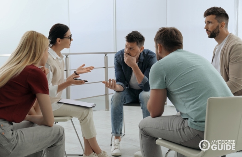 Psicólogo social discutiendo con un grupo de adultos