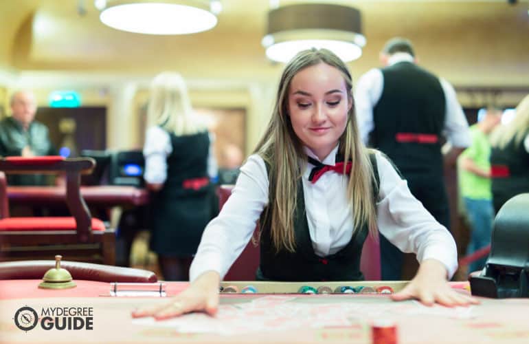 trabajador del casino arreglando cartas en una mesa de póquer