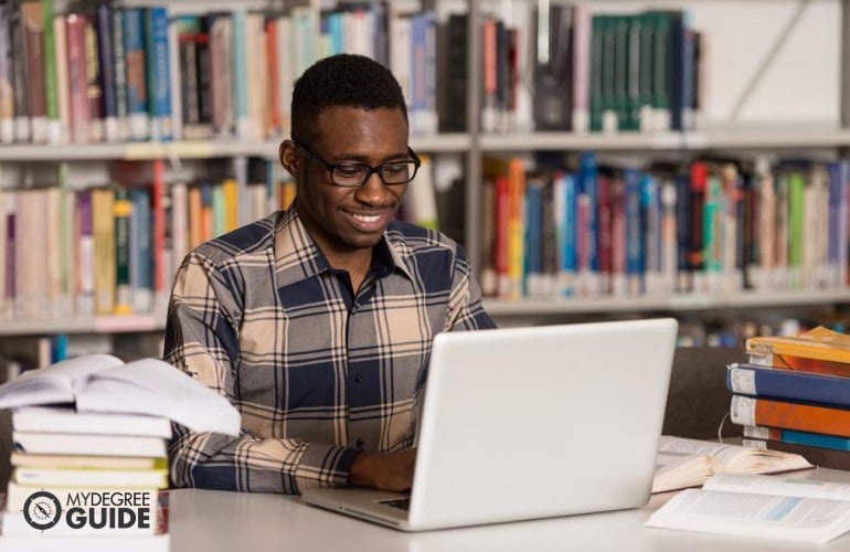 Estudiante de Licenciatura en Ingeniería Informática estudiando en línea en una biblioteca