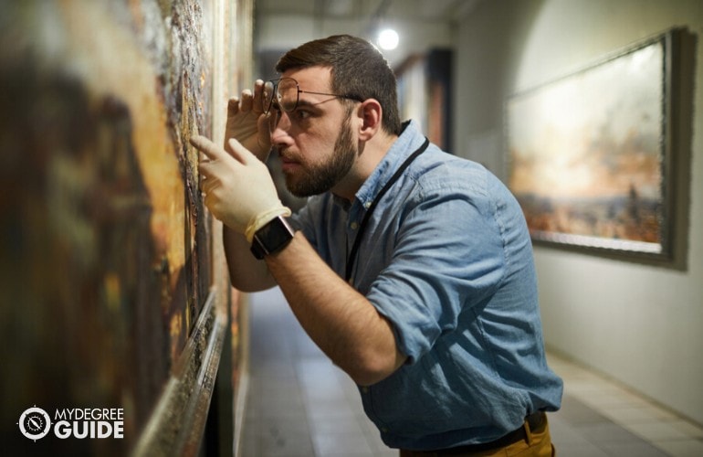 curador del museo revisando las pinturas en un museo