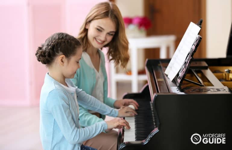 profesora de música enseñando a su estudiante a tocar el piano