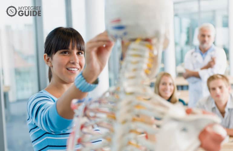 estudiantes de medicina estudiando un esqueleto modelo