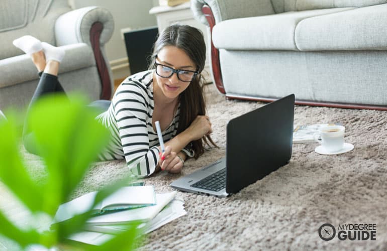mujer adulta estudiando cómodamente en casa con computadora y libros
