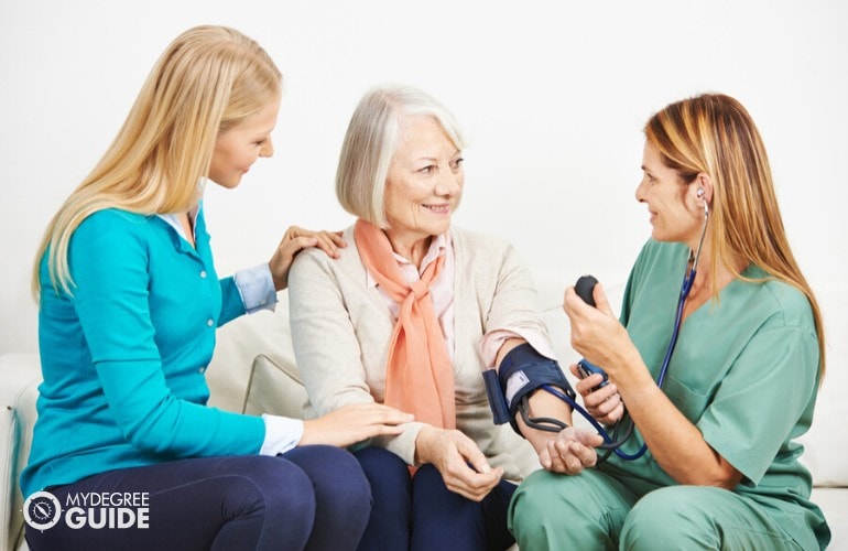 enfermera familiar comprobando la presión arterial de una anciana